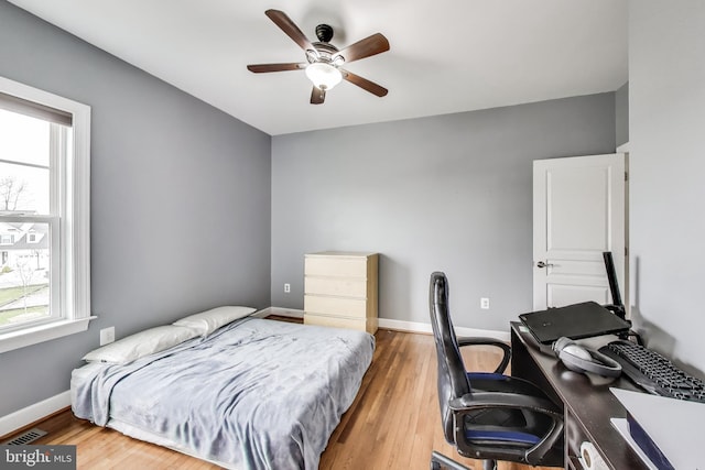 bedroom featuring wood finished floors, baseboards, a ceiling fan, and visible vents