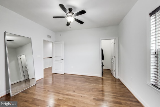 unfurnished bedroom featuring wood finished floors, baseboards, a ceiling fan, and visible vents