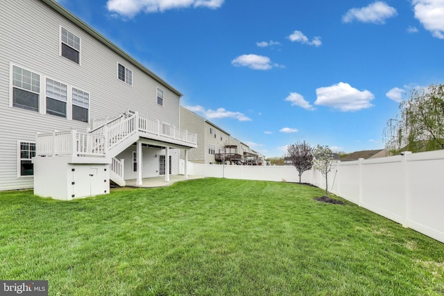 view of yard with a wooden deck, a fenced backyard, a patio area, and stairs