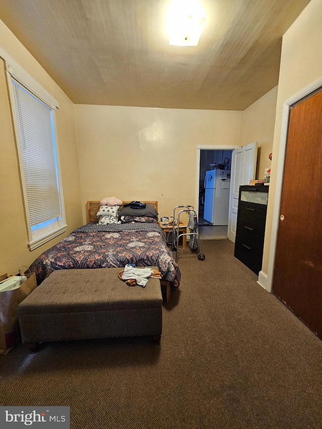 carpeted bedroom with freestanding refrigerator
