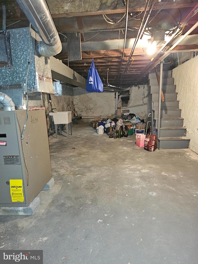 unfinished basement with stairs, a sink, and heating unit