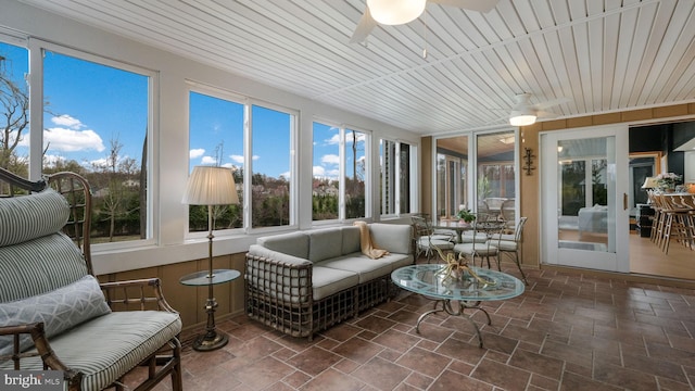 sunroom / solarium featuring an outdoor living space, ceiling fan, and stone tile flooring
