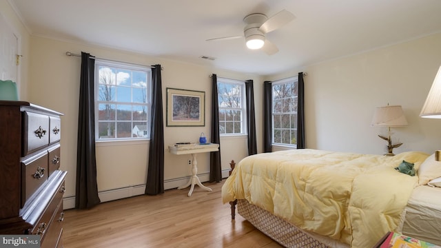 bedroom with a baseboard heating unit, ornamental molding, visible vents, ceiling fan, and light wood finished floors
