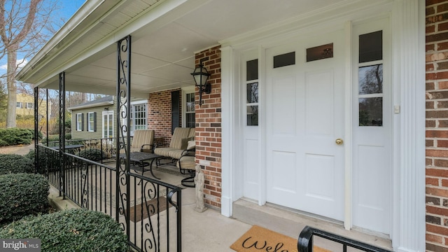 entrance to property featuring brick siding and covered porch