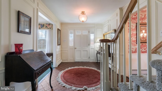 foyer entrance with a decorative wall, ornamental molding, and stairway