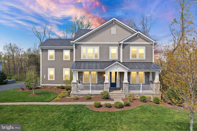 craftsman inspired home with a front yard, a porch, stone siding, and metal roof