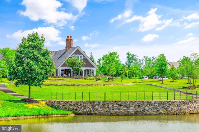 view of property's community with a yard, fence, and a water view