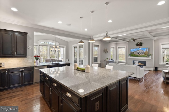 kitchen featuring tasteful backsplash, a kitchen island, dark wood-type flooring, stainless steel dishwasher, and ceiling fan with notable chandelier