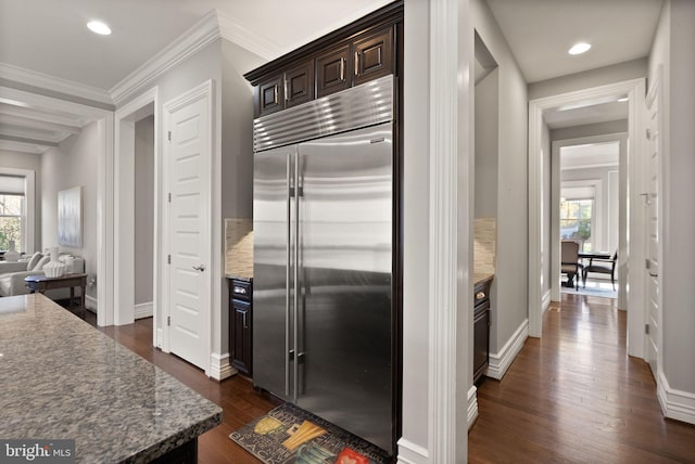 kitchen featuring dark brown cabinetry, dark wood-type flooring, ornamental molding, baseboards, and stainless steel built in fridge