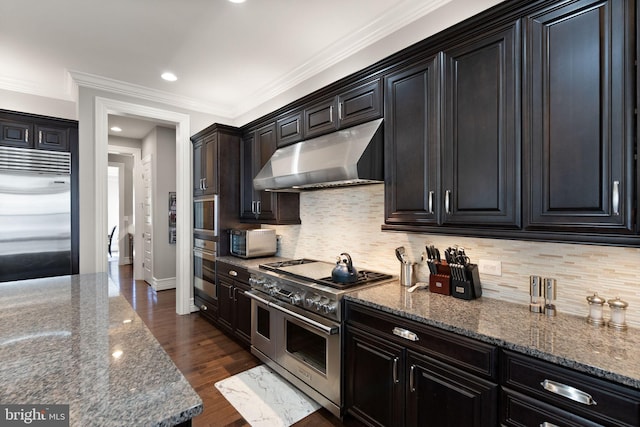 kitchen with baseboards, premium appliances, dark wood finished floors, under cabinet range hood, and dark stone counters