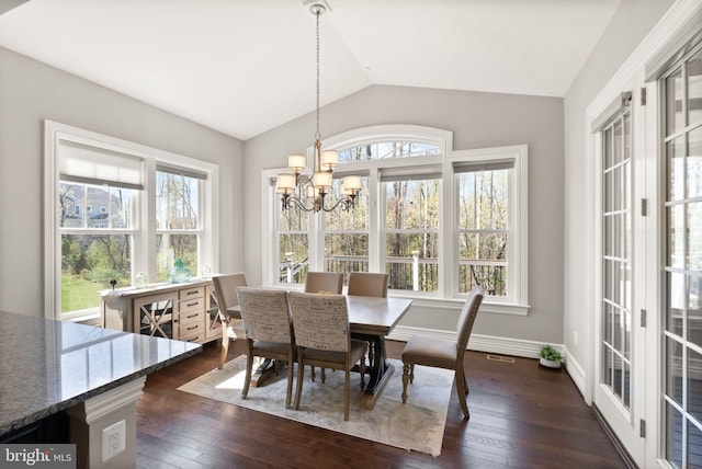 dining area featuring a wealth of natural light, a notable chandelier, vaulted ceiling, and dark wood finished floors