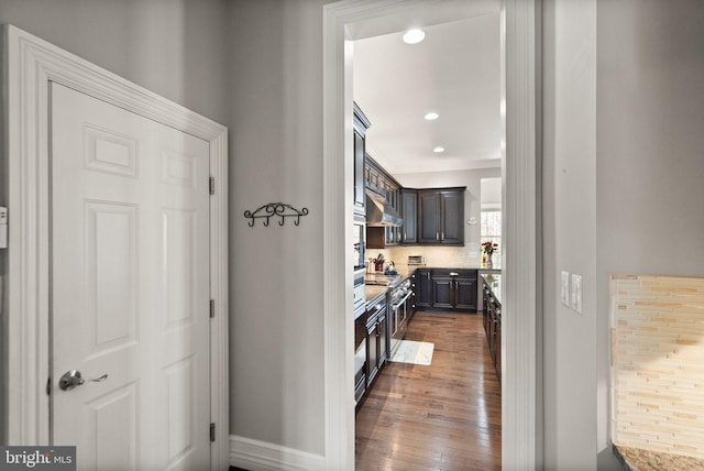 corridor featuring recessed lighting, dark wood-style flooring, baseboards, and ornamental molding