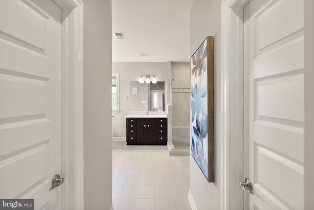 full bathroom with vanity, baseboards, tile patterned floors, tiled shower, and visible vents