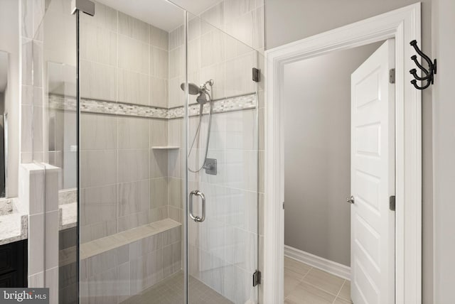 full bath featuring a shower stall, tile patterned floors, vanity, and baseboards