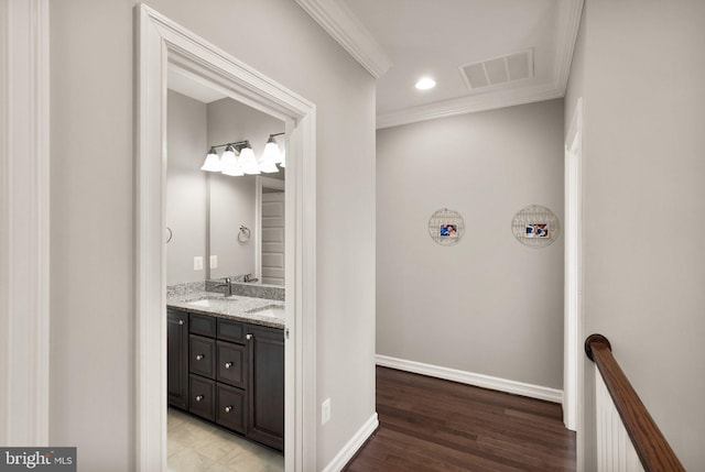 bathroom with ornamental molding, visible vents, wood finished floors, a sink, and double vanity