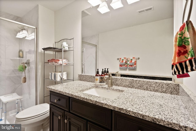 bathroom featuring toilet, a stall shower, vanity, and visible vents