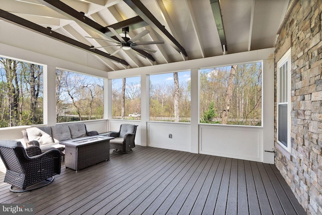 sunroom featuring beamed ceiling, a ceiling fan, and an outdoor hangout area