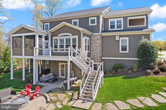 rear view of property with an outdoor living space with a fire pit, a patio area, stairs, a yard, and a sunroom