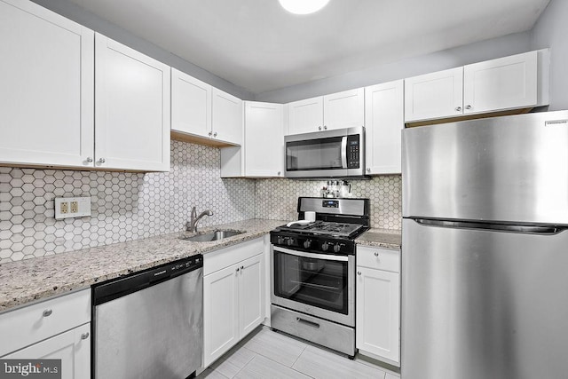 kitchen featuring a sink, appliances with stainless steel finishes, white cabinets, and light stone countertops