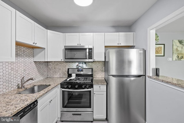 kitchen with a sink, white cabinetry, decorative backsplash, and stainless steel appliances