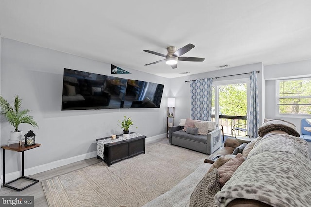 living room with baseboards, visible vents, ceiling fan, and wood finished floors