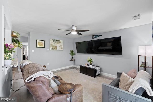 living room with visible vents, a ceiling fan, and baseboards