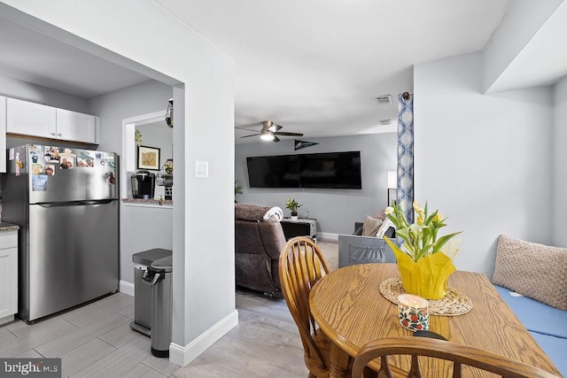 dining area with light wood-style floors, baseboards, ceiling fan, and visible vents