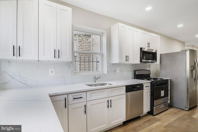 1820 Aiken St, Baltimore, MD 21213 - kitchen with white cabinets, light wood-type flooring, a sink, and appliances with stainless steel finishes