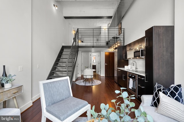 1401 R St NW Unit 304, Washington, DC 20009 - living room featuring dark wood-type flooring, baseboards, a towering ceiling, and stairway