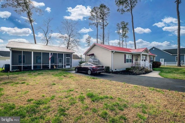 129 Prince Georges Dr, Dagsboro, DE 19939 - view of front of house with a sunroom, a front yard, driveway, and metal roof