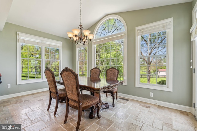 dining space featuring an inviting chandelier, baseboards, stone tile flooring, and lofted ceiling