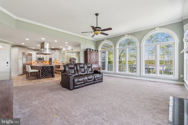 living room with a ceiling fan, ornamental molding, a healthy amount of sunlight, and light carpet