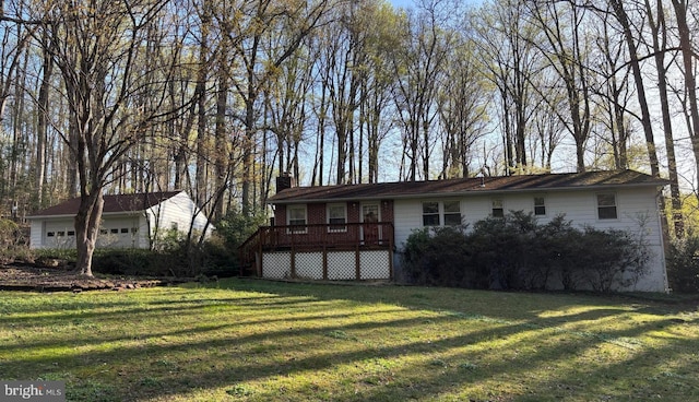 single story home featuring a detached garage, a deck, a chimney, and a front yard