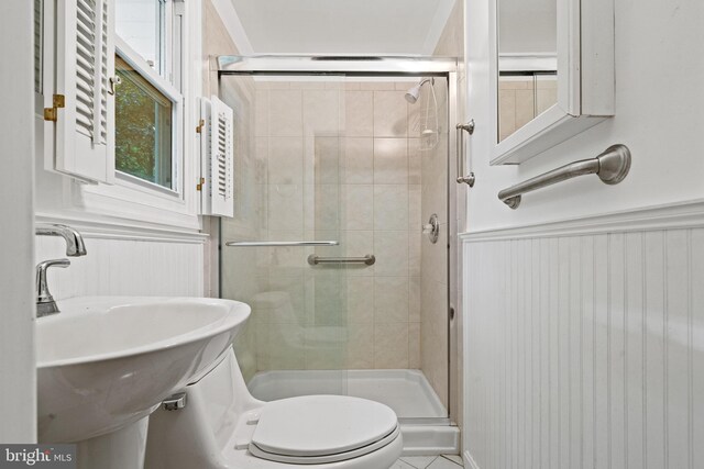 bathroom featuring a sink, wainscoting, a shower stall, and toilet