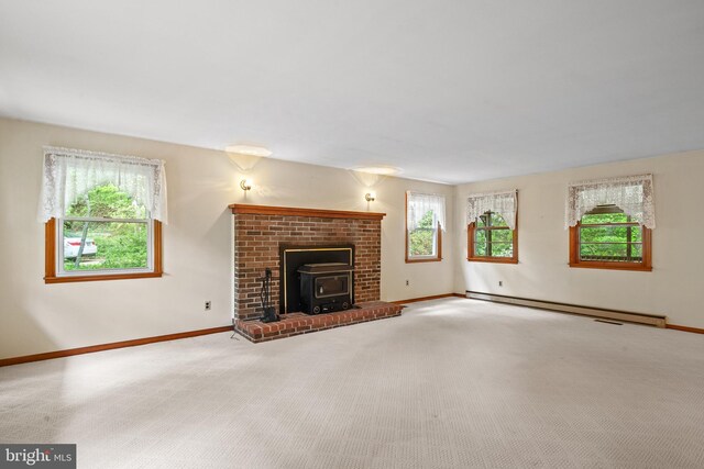 unfurnished living room with baseboards, a wood stove, carpet, and a baseboard heating unit