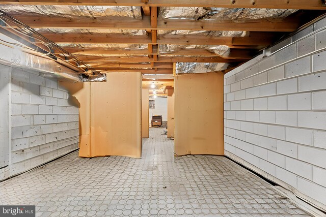 unfinished basement with concrete block wall and light floors
