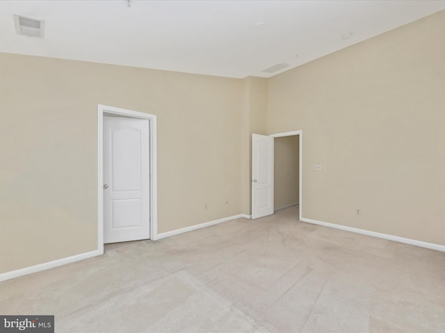 spare room featuring light colored carpet, baseboards, and visible vents
