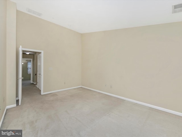 unfurnished room with visible vents, light colored carpet, and baseboards