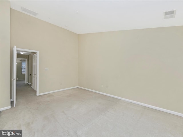 spare room featuring visible vents, light colored carpet, and baseboards