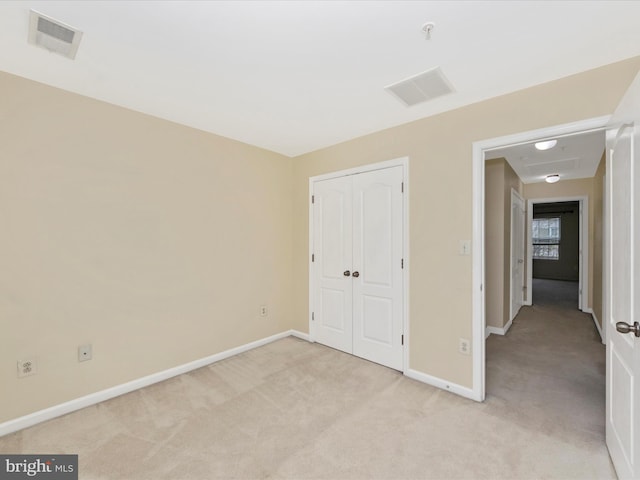 unfurnished bedroom with a closet, light colored carpet, baseboards, and visible vents