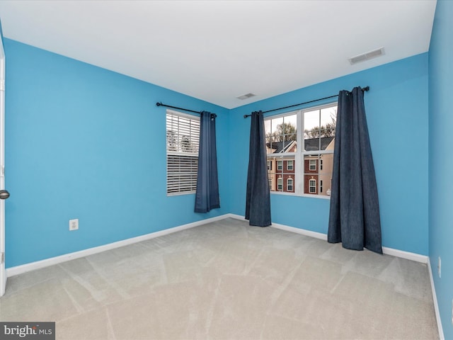empty room with carpet flooring, visible vents, and baseboards
