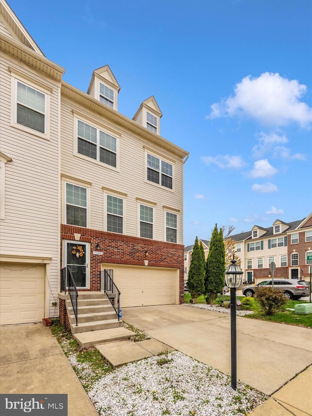 townhome / multi-family property with a garage, driveway, and brick siding