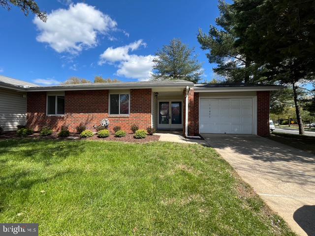single story home featuring a garage, a front yard, driveway, and brick siding