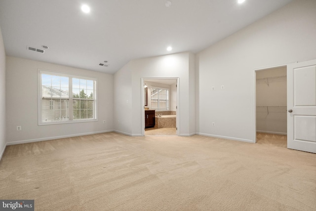 unfurnished bedroom featuring lofted ceiling, a spacious closet, light carpet, multiple windows, and recessed lighting