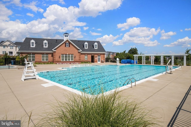 community pool with a pergola, fence, and a patio