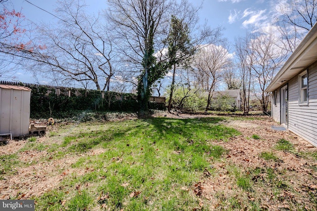 view of yard with a fenced backyard, a storage shed, and an outbuilding