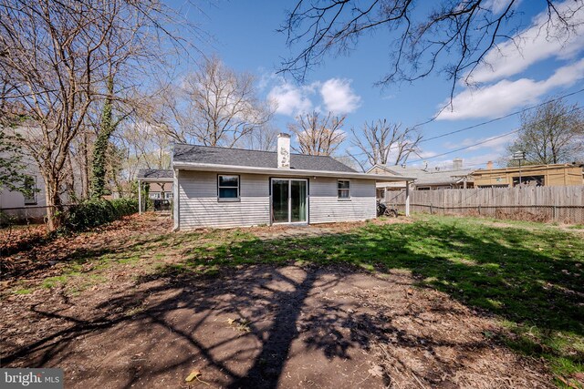 back of house with a yard, fence, and a chimney