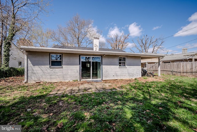 rear view of house with a chimney, fence, and a lawn