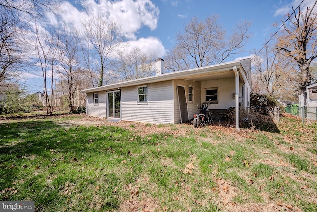 rear view of house featuring fence, a lawn, and a chimney