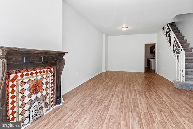 unfurnished living room with light wood-style flooring, baseboards, and stairs